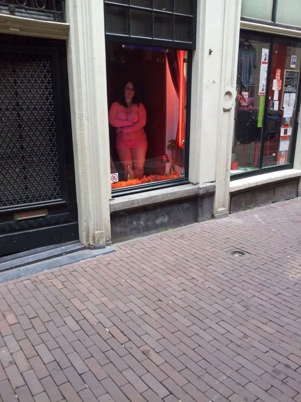 Проститутка в витрине борделя заманивает клиентов с улицы 1 фото