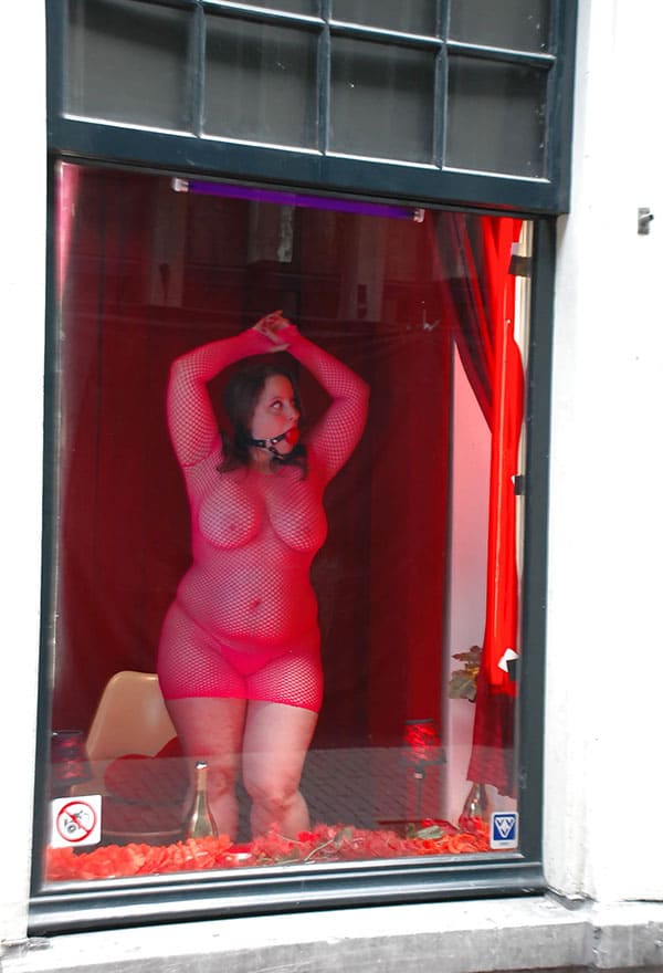 Проститутка в витрине борделя заманивает клиентов с улицы 10 фото