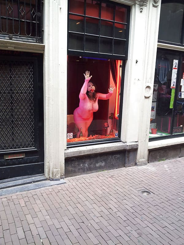 Проститутка в витрине борделя заманивает клиентов с улицы 12 фото