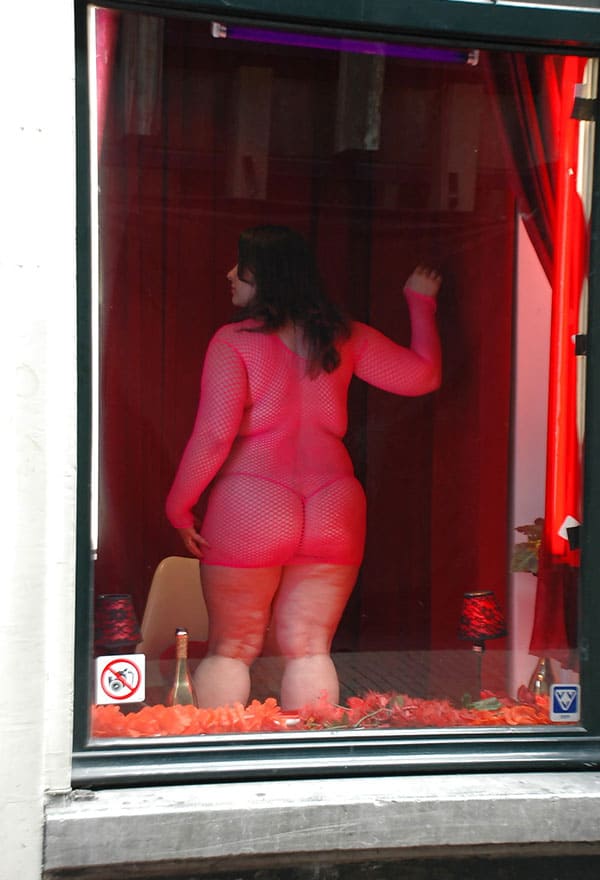 Проститутка в витрине борделя заманивает клиентов с улицы 7 фото