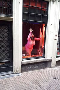 Проститутка в витрине борделя заманивает клиентов с улицы
