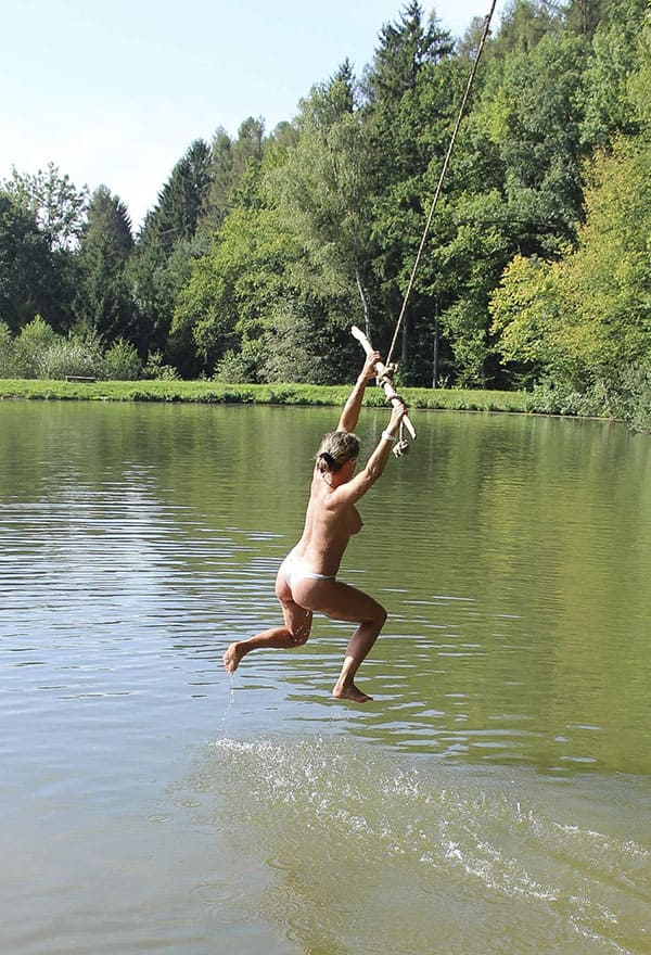 Веселая нудистка ныряет с тарзанки в озеро 6 фото
