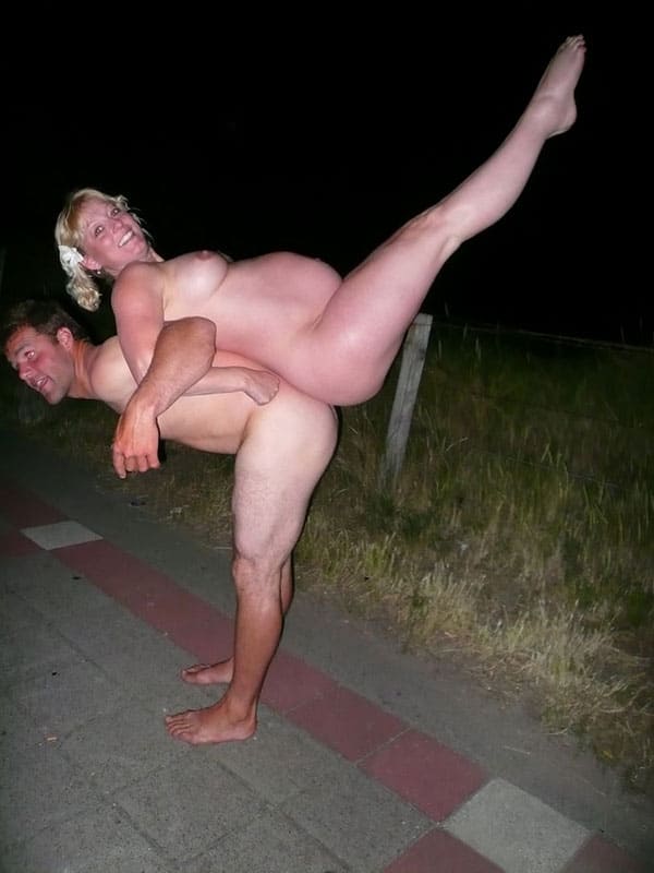 Муж с беременной женой занимаются голой гимнастикой на ночной улице